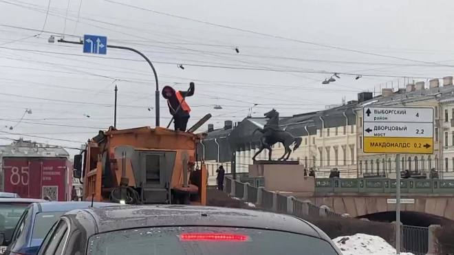 Коммунальщик сбрасывал песок на тротуар, находясь в кузове грузовика, на набережной Фонтанки